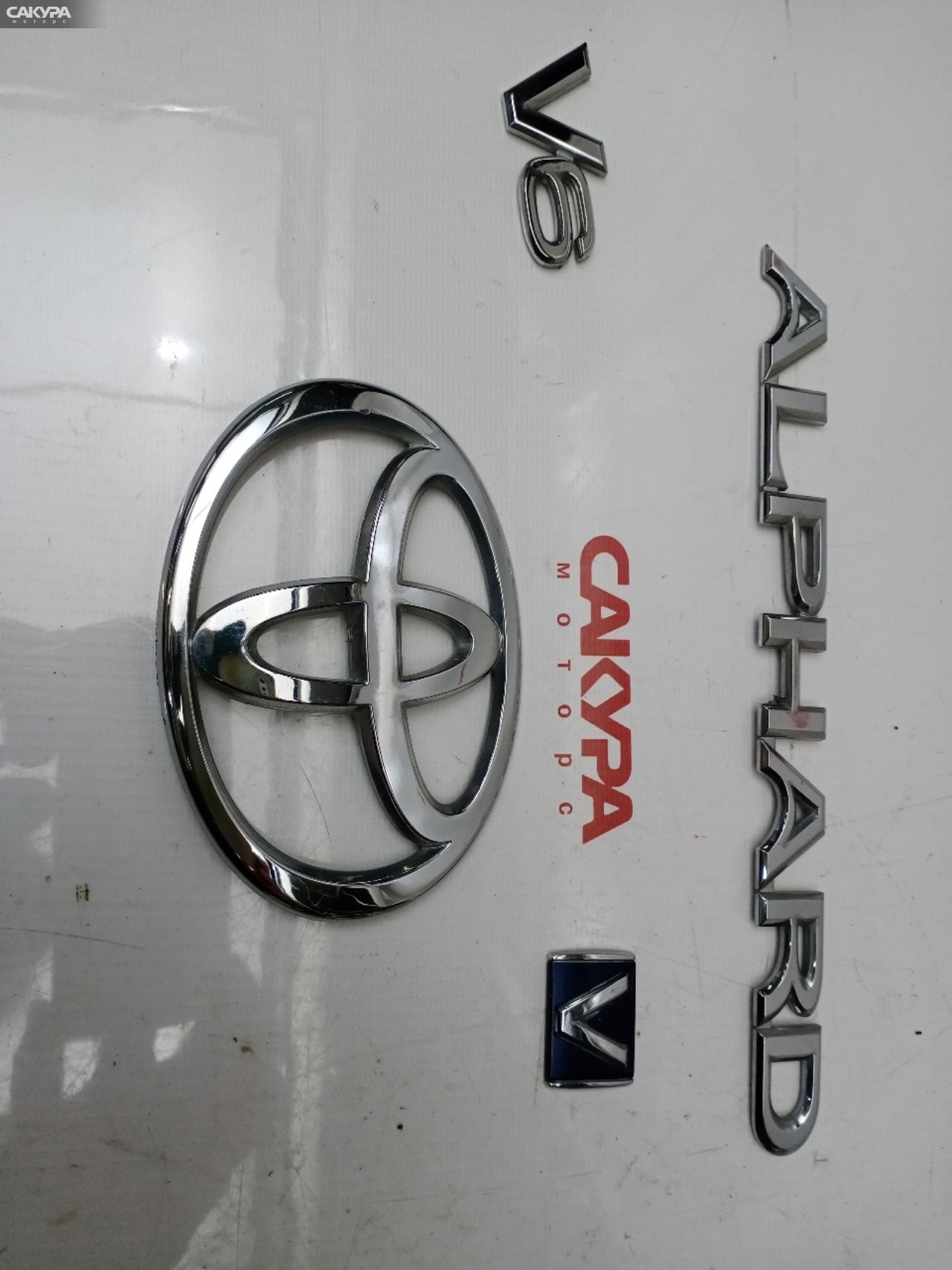 Эмблема Toyota Alphard MNH10W 1MZ-FE: купить в Сакура Красноярск.